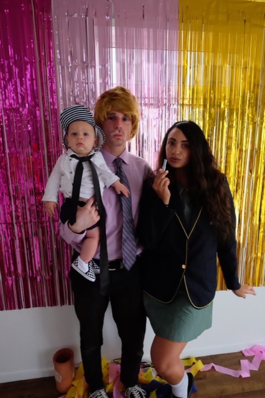 A playful costume photo with loved ones in front of shiny streamers.